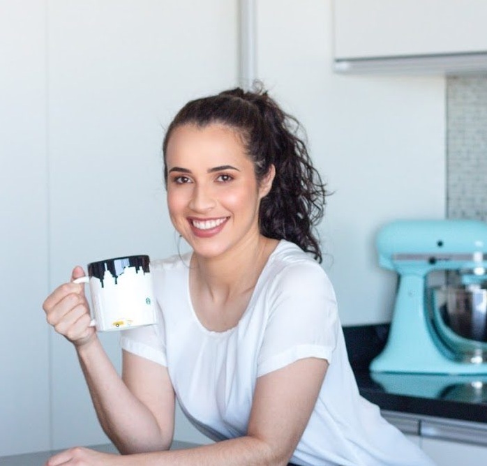 A mentora sorrindo na cozinha, segurando uma caneca