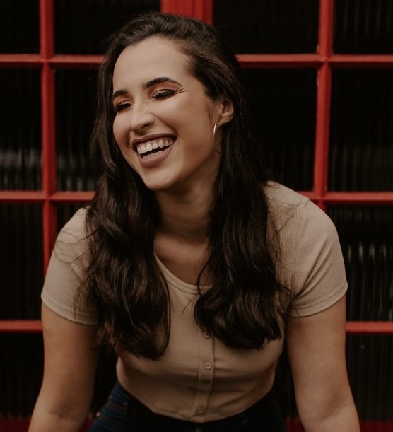 A mentora sorrindo diante de uma janela vermelha